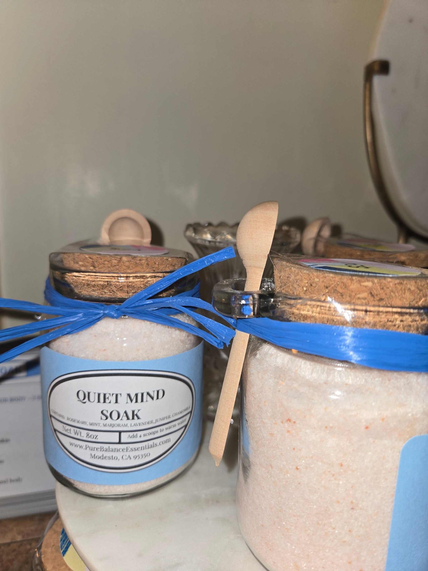 Glass jar of Quiet Mind Soak pink Himalayan salt bath soak with stainless steel spoon for relaxation and aromatherapy