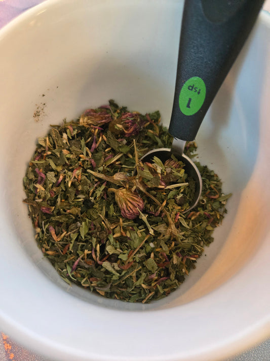 Cup of organic 21st Century Herbal Tea with herbs and flowers on wooden table