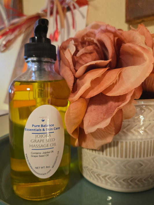 Jojoba with grapeseed oil for pain relief, 8oz bottle, next to decorative flowers.